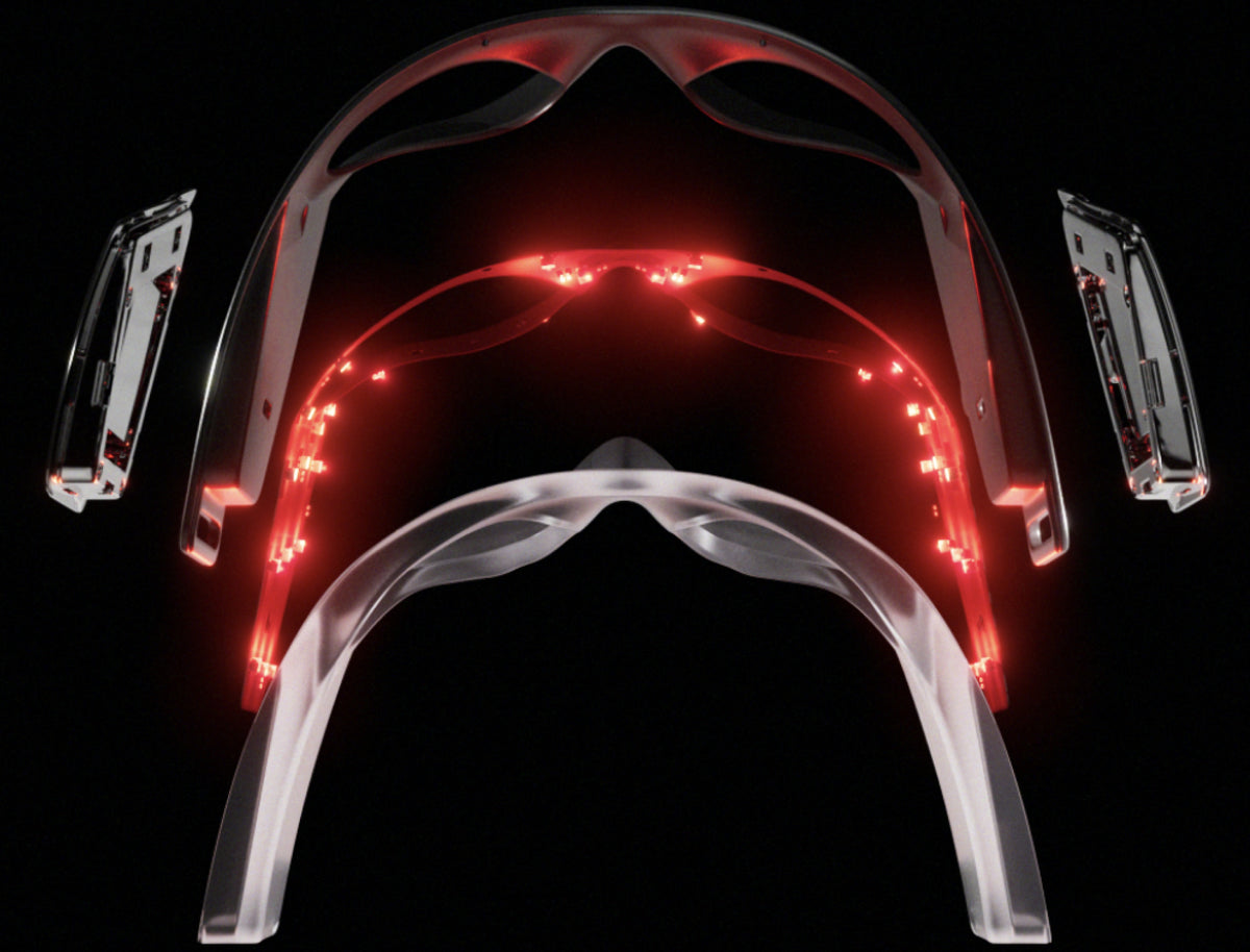 Transparent wearable smart glasses frame with red LED lights and detachable electronic components against black background