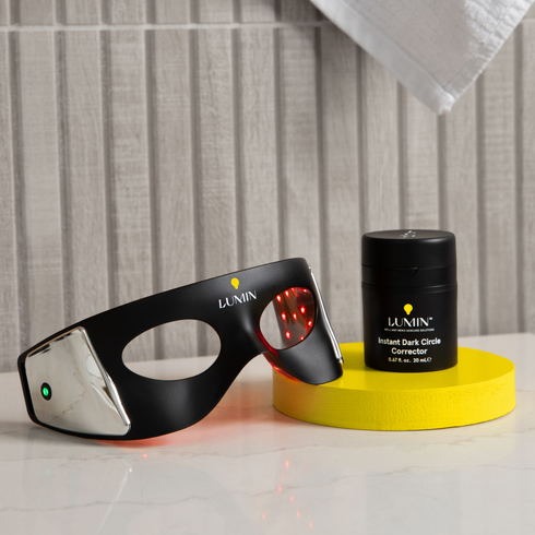 Lumin men's skincare LED eye mask with red light therapy and Instant Dark Circle Corrector cream on yellow platform
