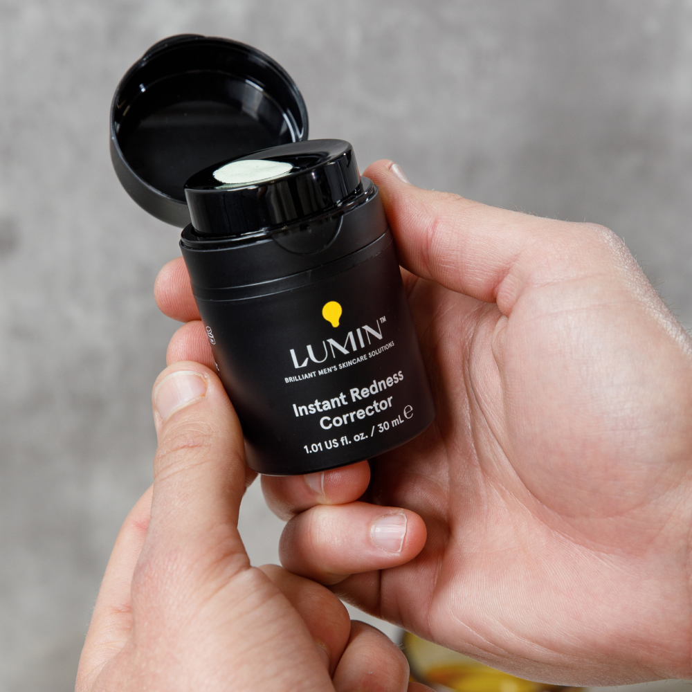 Lumin Instant Redness Corrector in black container held in hand, men's skincare cream for redness relief, 30ml.