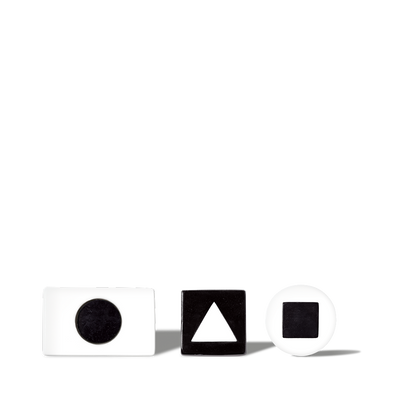 White and black geometric shape blocks with circle, triangle, and square cutouts on black background for educational use.