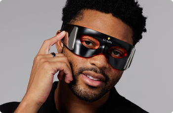 Man wearing black LED eye mask with red light therapy, promoting skincare and relaxation technology for wellness.