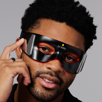 Man wearing futuristic black LED eye mask with red light therapy for skincare and relaxation benefits